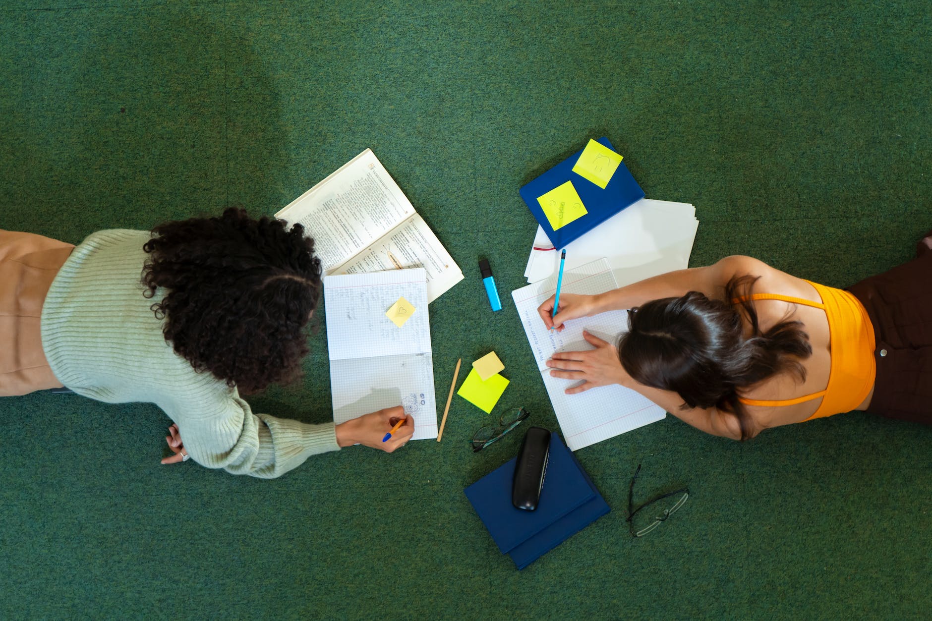 Engaged in a Focused Study Session: Two Female Students with Open Books and Pens